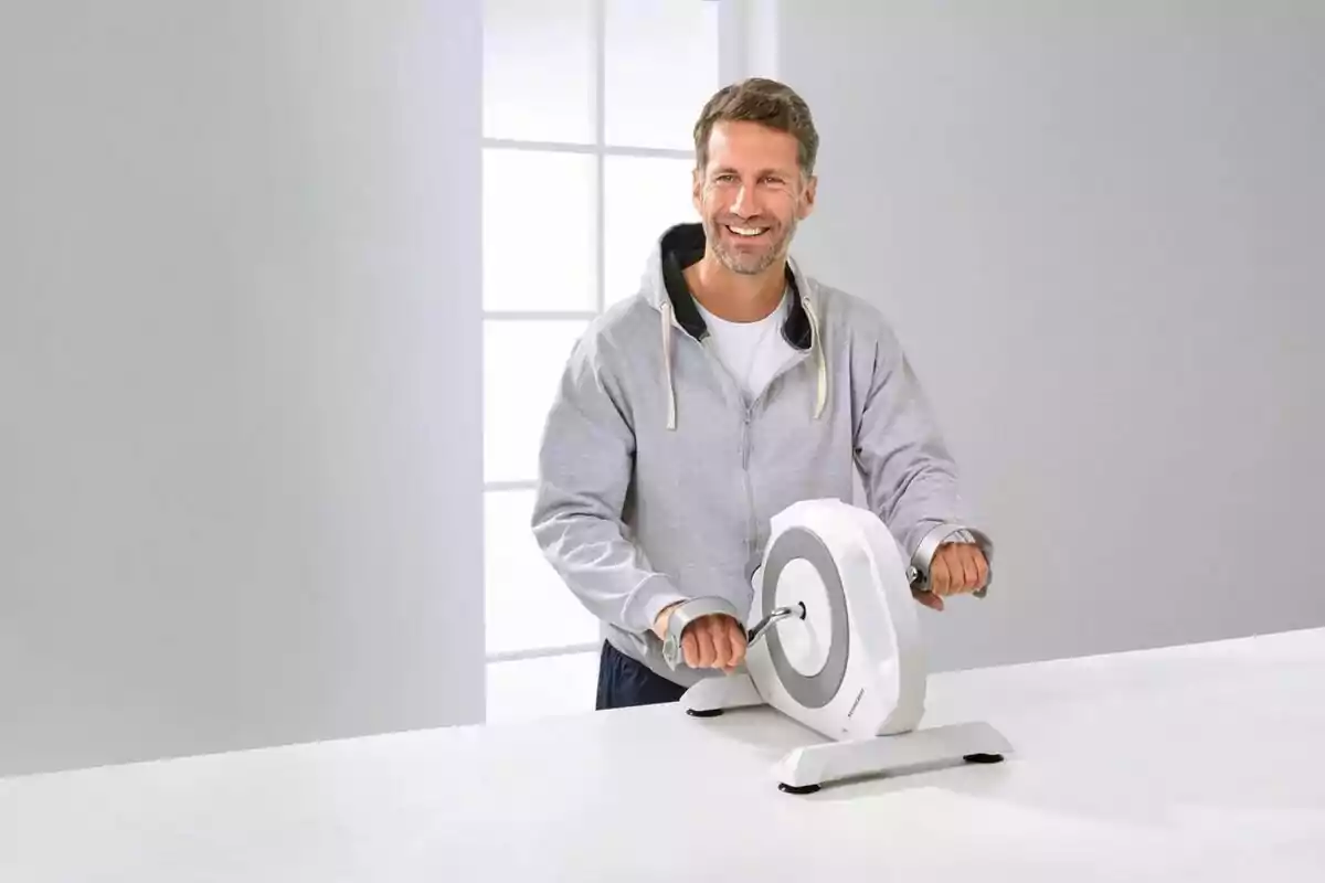 Home somrient utilitzant una màquina d’exercici per a braços en una habitació il·luminada