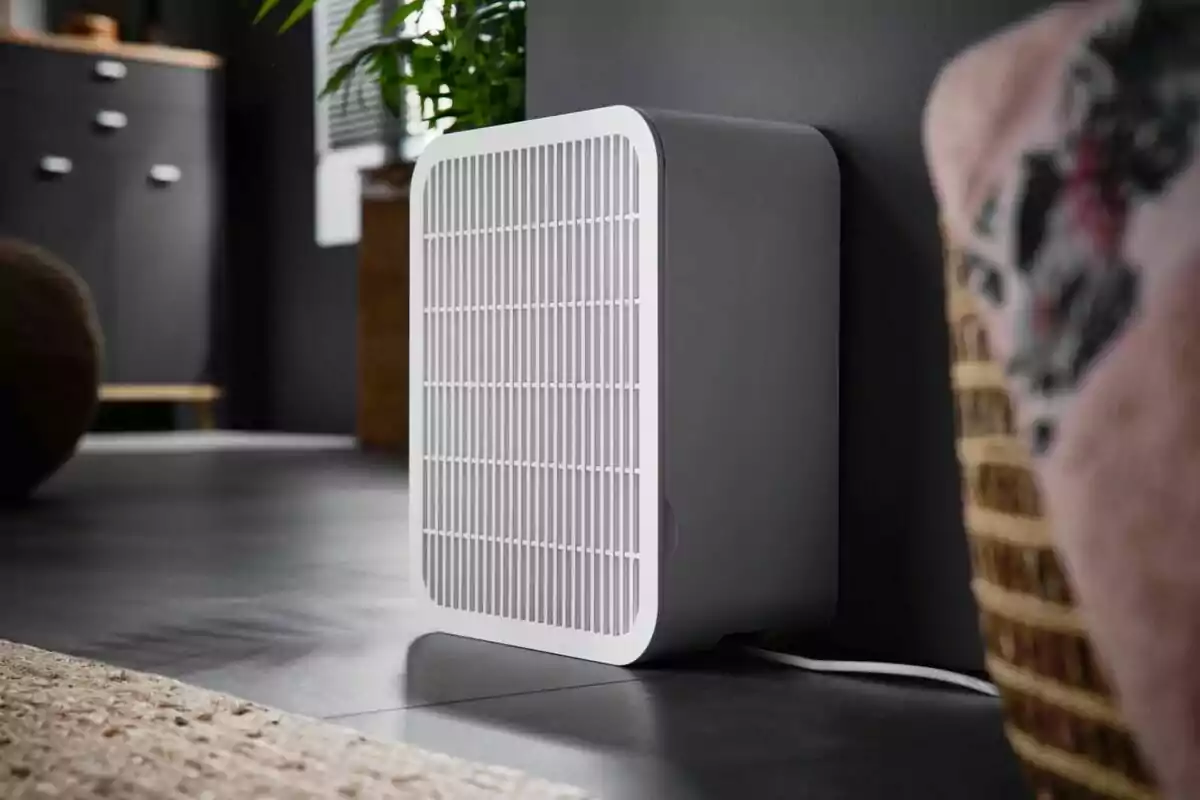 Purificador d’aire blanc col·locat a terra al costat d’una paret en una habitació moderna