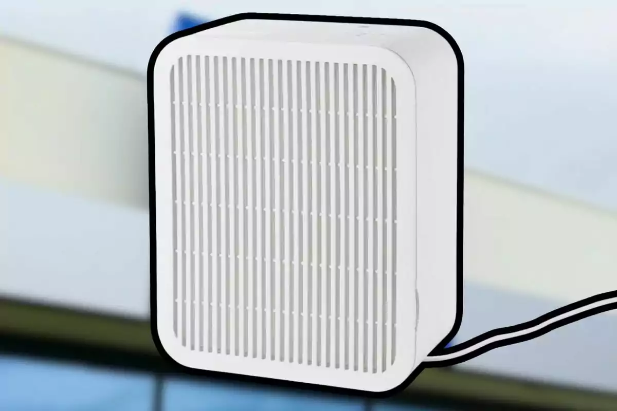 Dispositiu blanc rectangular amb reixetes verticals i un cable negre connectat, sobre un fons desenfocat.