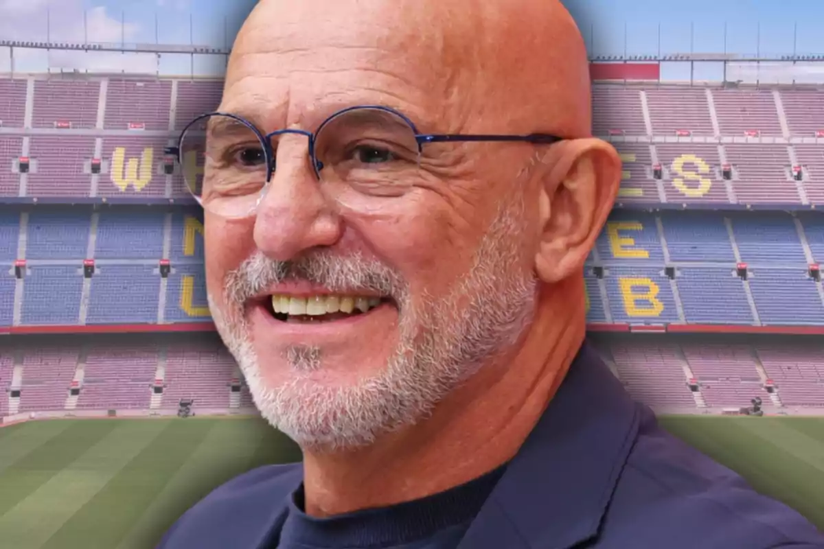 Hombre calvo con gafas y barba sonriente frente a un estadio de fútbol vacío