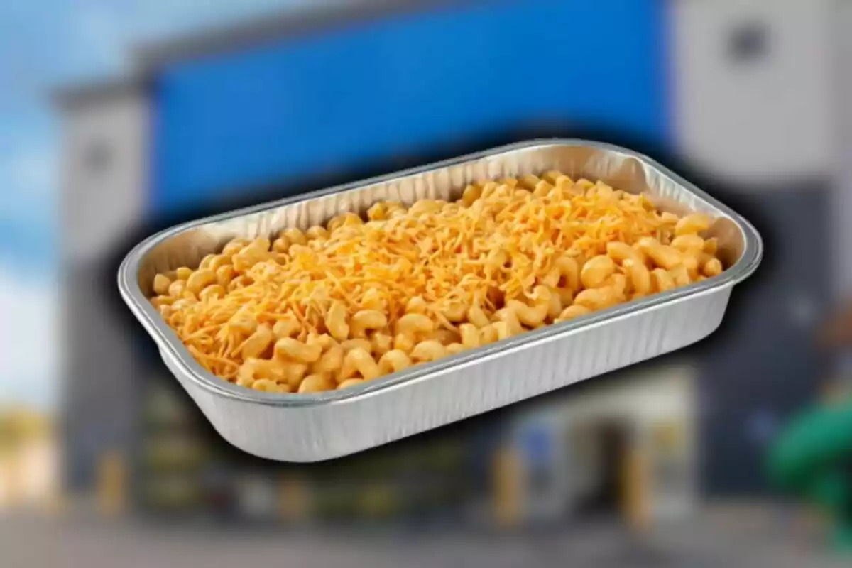 Bandeja de aluminio llena de macarrones con queso rallado encima con un fondo desenfocado de Sam's Club.