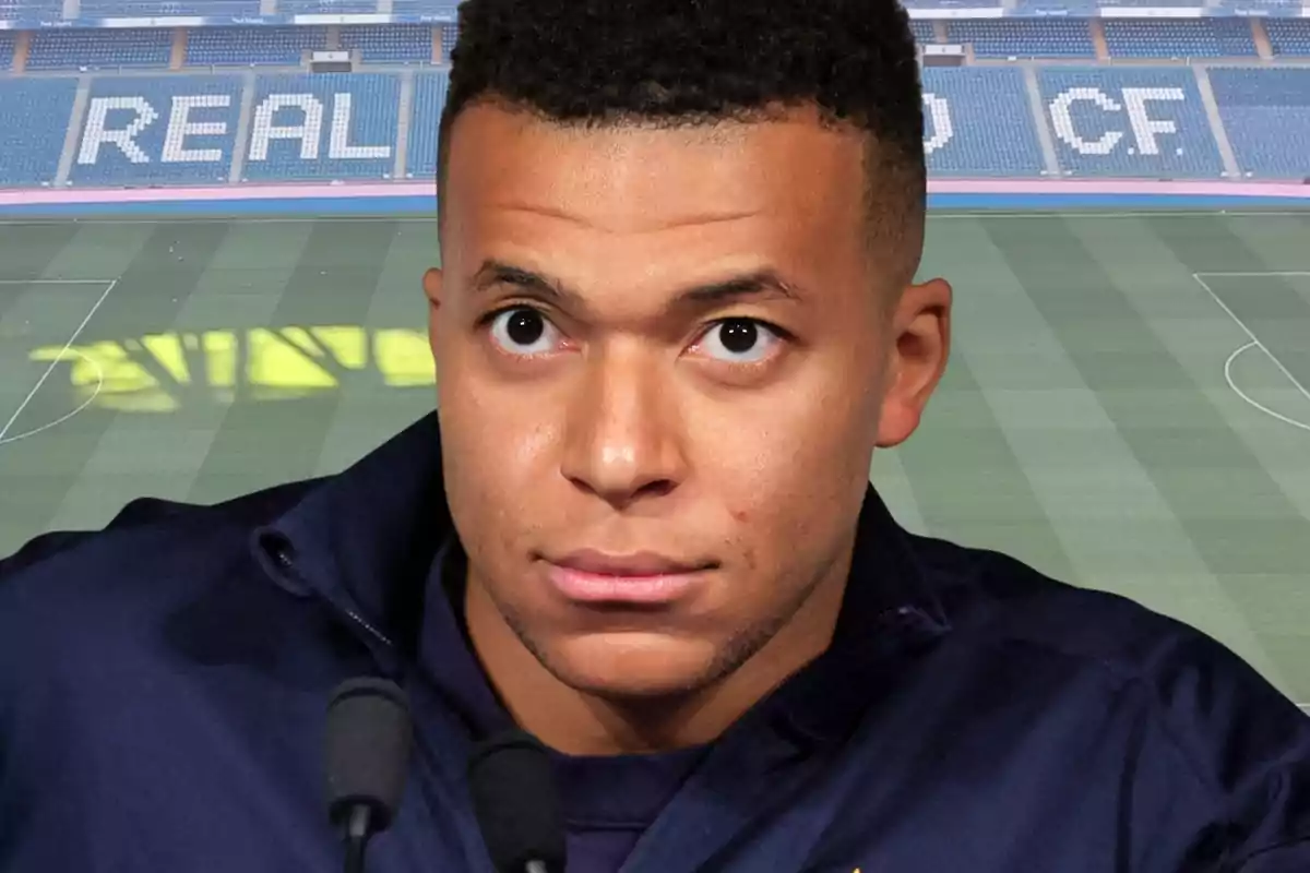 Un futbolista en primer pla davant d’un estadi amb les grades que formen la paraula REAL