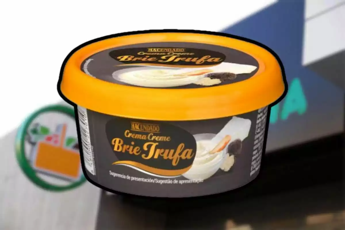 Envàs de crema de formatge brie amb tòfona de la marca Hacendado amb tapa taronja sobre un fons borros de supermercat