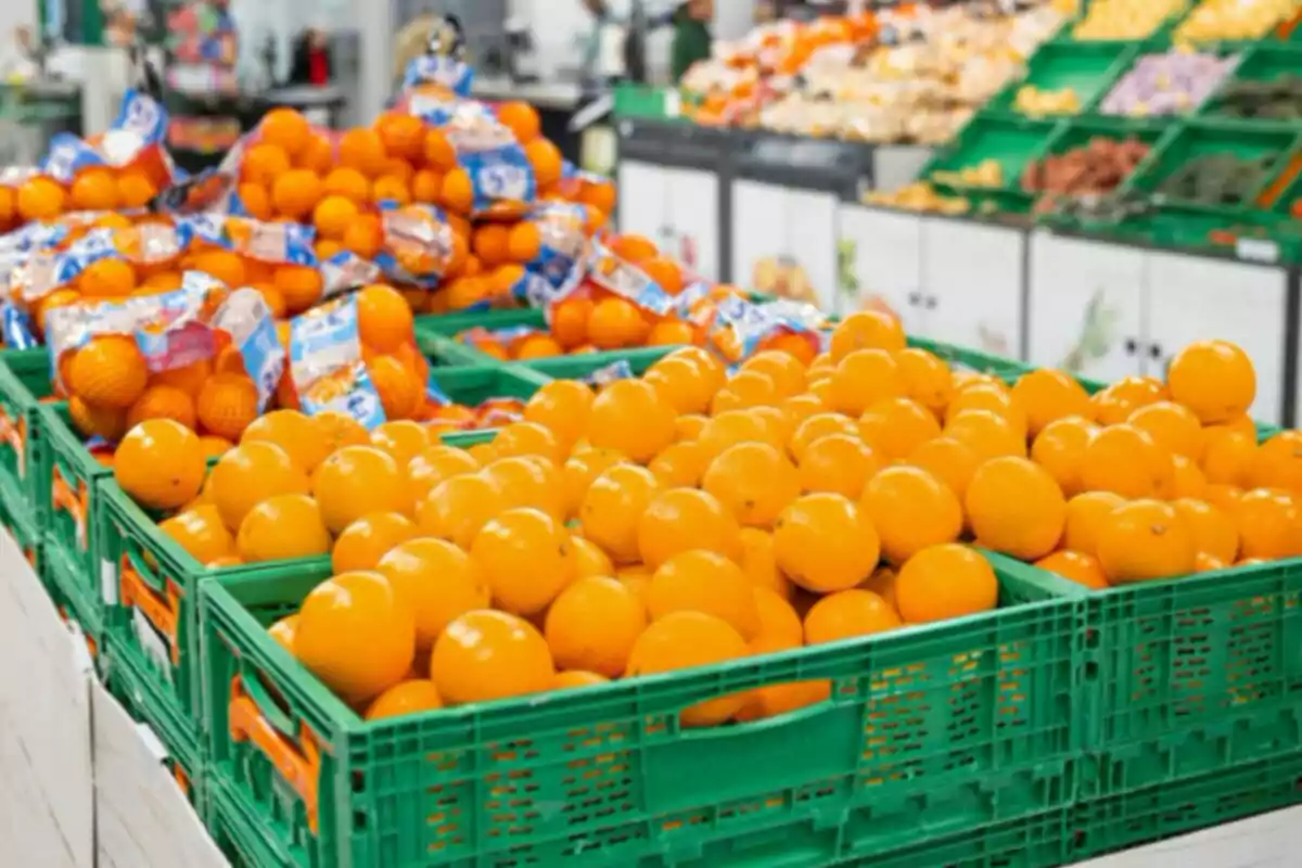 Taronges fresques col·locades en caixes verdes dins d’una botiga o supermercat