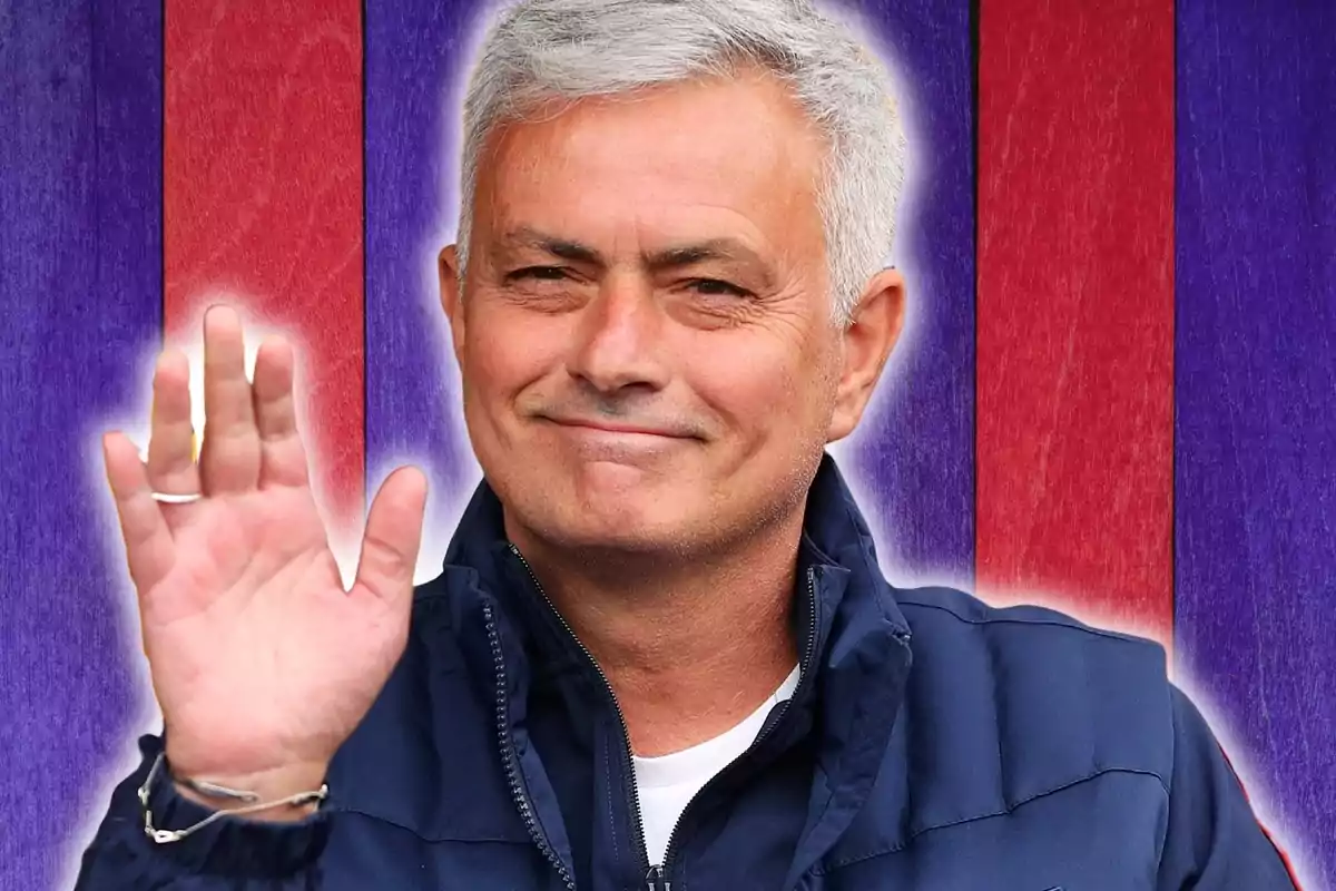 Home de cabells canosos somrient saludant amb la mà aixecada davant d’un fons de franges vermelles i morades