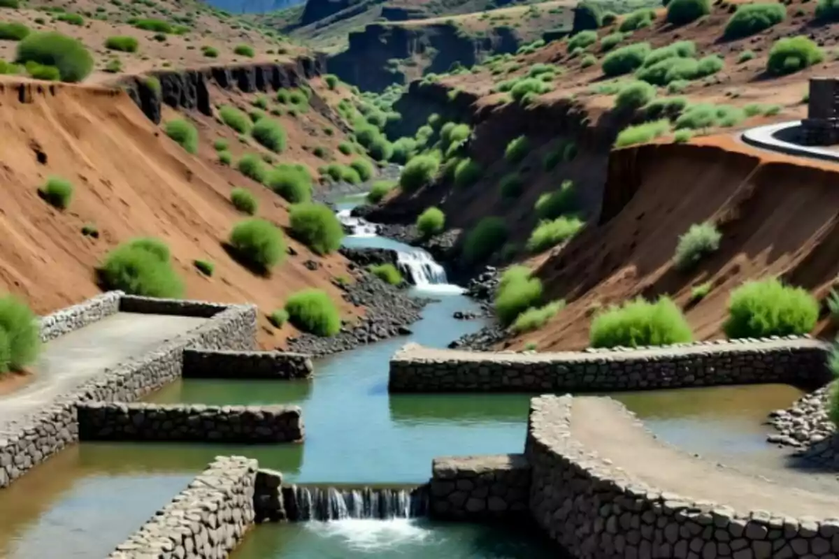 Un río fluye entre colinas áridas con vegetación dispersa y estructuras de piedra que forman pequeñas represas en el agua en Canarias. Un río fluye entre colinas áridas con vegetación dispersa y estructuras de piedra que forman pequeñas represas en el agua en Canarias.