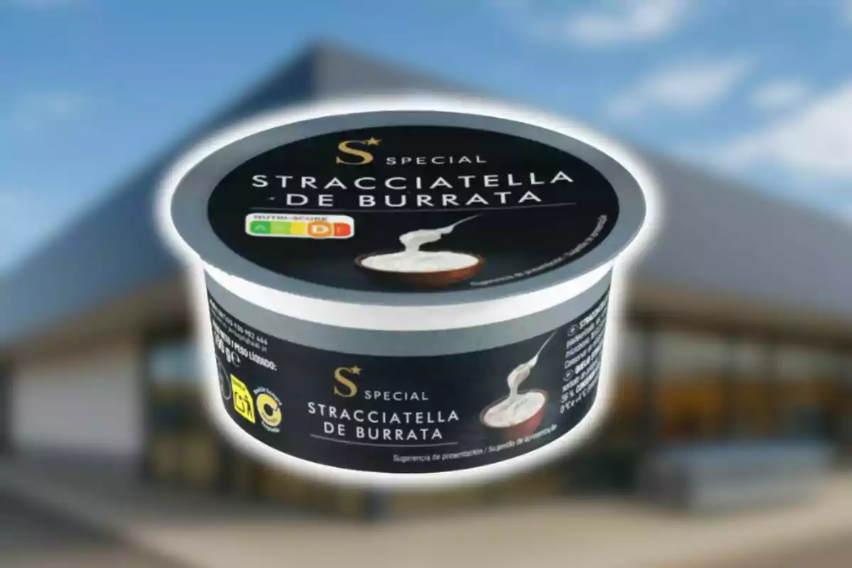 Envàs de stracciatella de burrata de la marca Special d’Aldi amb un fons desenfocat d’un edifici.