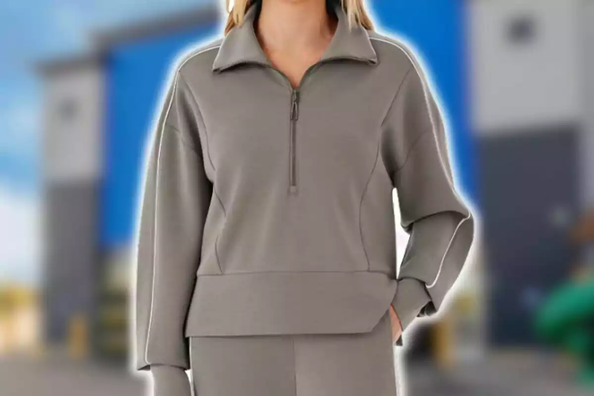 Woman wearing a gray sports outfit with a zip-up collar and a blurred background of a blue and gray building.