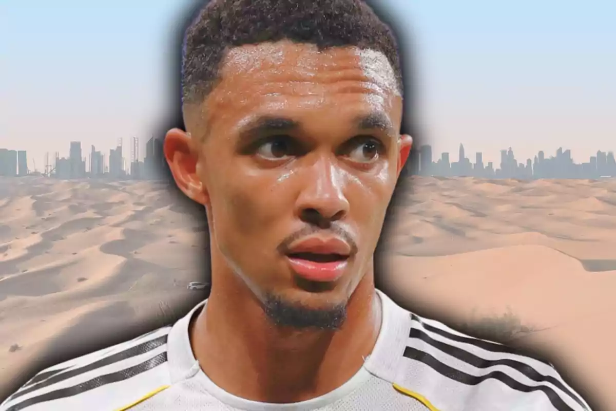 Futbolista amb samarreta blanca i negra en primer pla sobre un fons de dunes de sorra i una ciutat moderna al fons