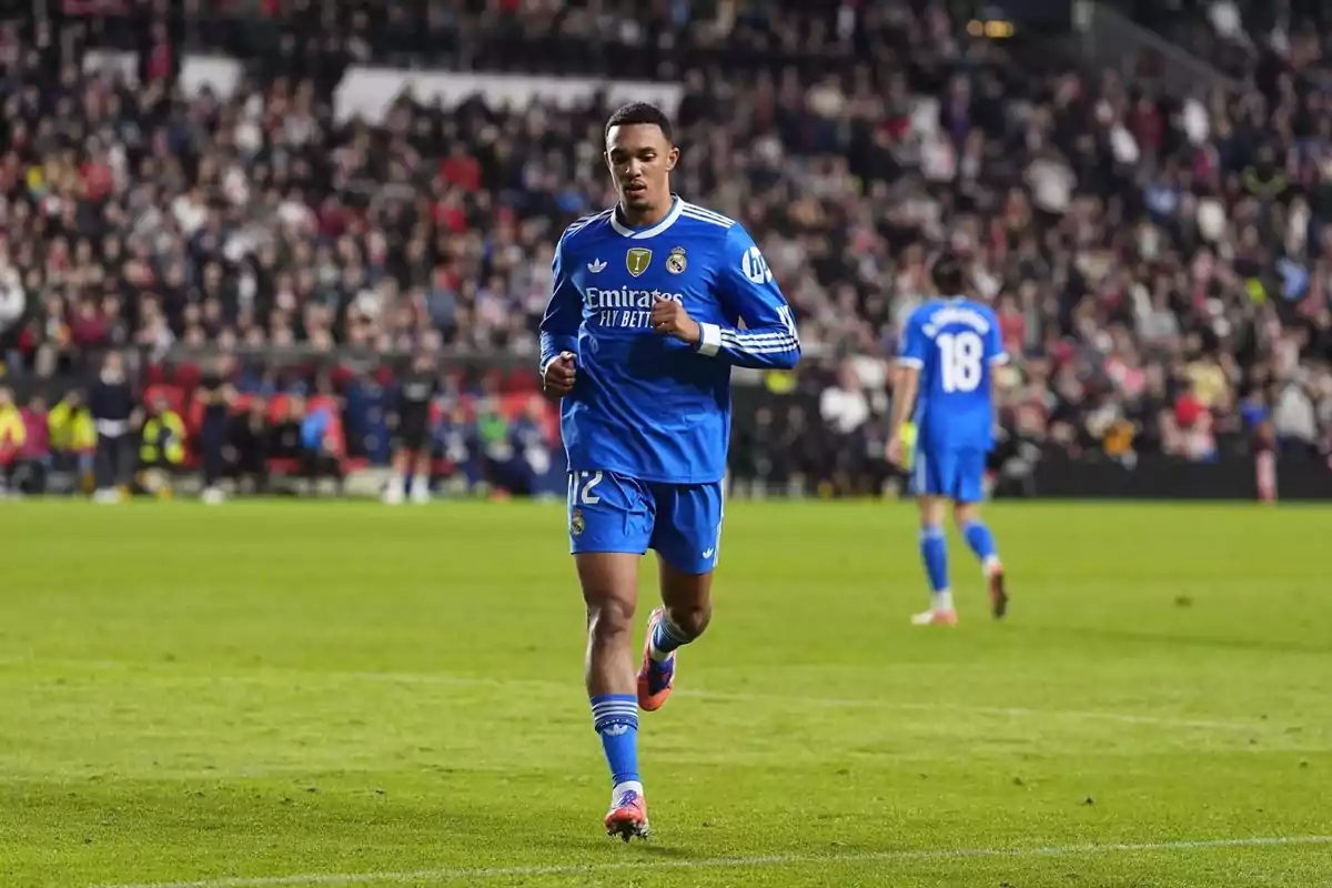 Futbolista del Reial Madrid amb uniforme blau corrent pel camp durant un partit amb el públic de fons