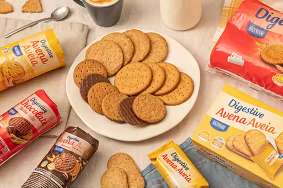 Galletas Digestive de diferentes sabores y presentaciones dispuestas alrededor de un plato con galletas y una taza de café