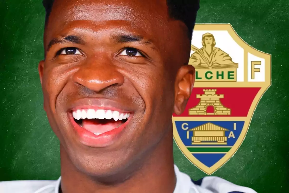 Un futbolista sonriente en primer plano con el escudo del Elche CF de fondo sobre una pizarra verde