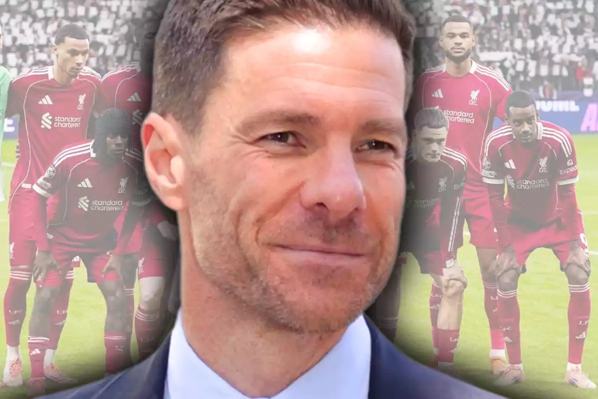 Un home somrient en primer pla amb un equip de futbol vestit de vermell al fons