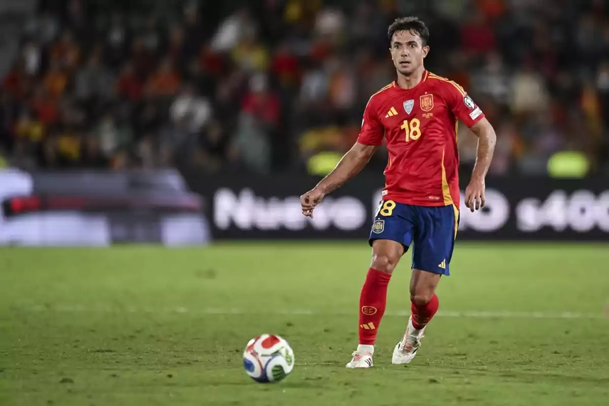Futbolista de la selección de España con el uniforme rojo y azul controlando el balón en un partido