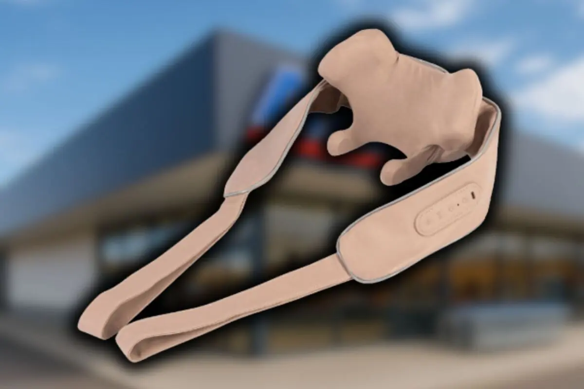 Cinturón masajeador beige de Aldi con forma de perro flotando frente a la fachada desenfocada de un supermercado de la cadena mencionada.