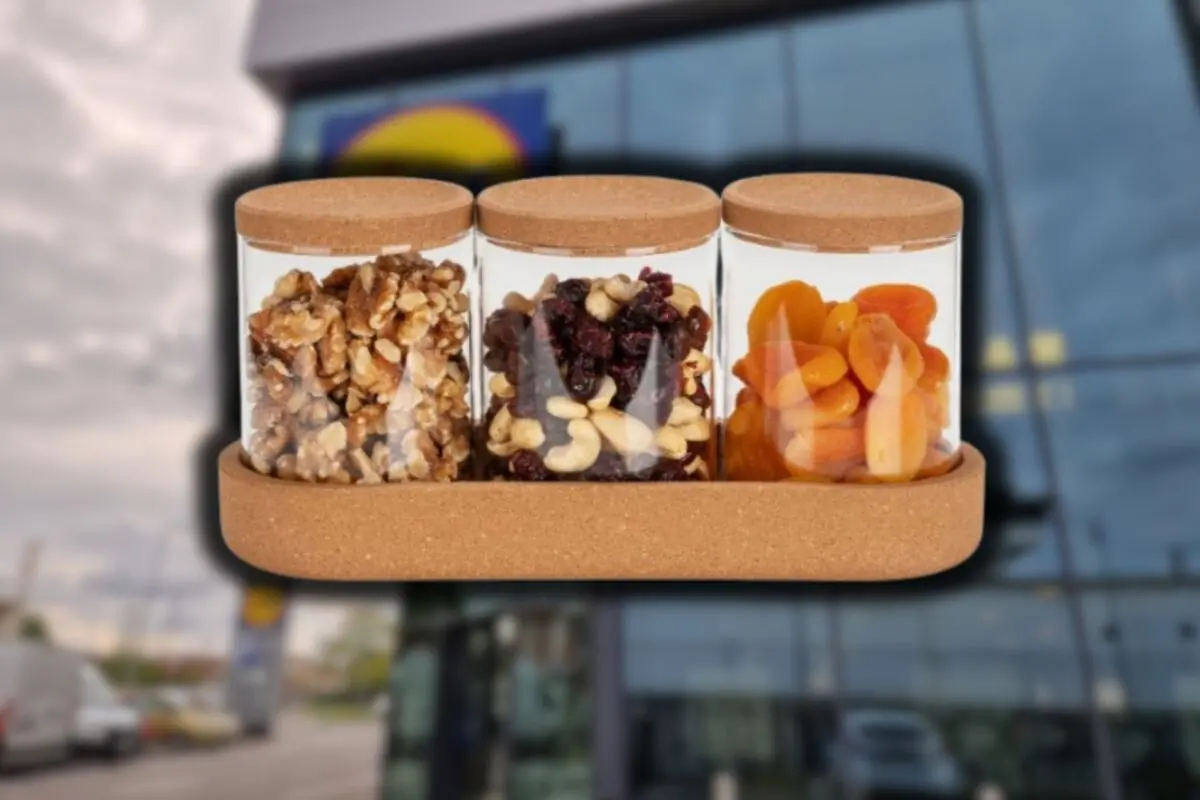 Three glass jars with cork lids contain nuts, dried fruits, and dried apricots, placed on a tray in front of a modern building with large windows.