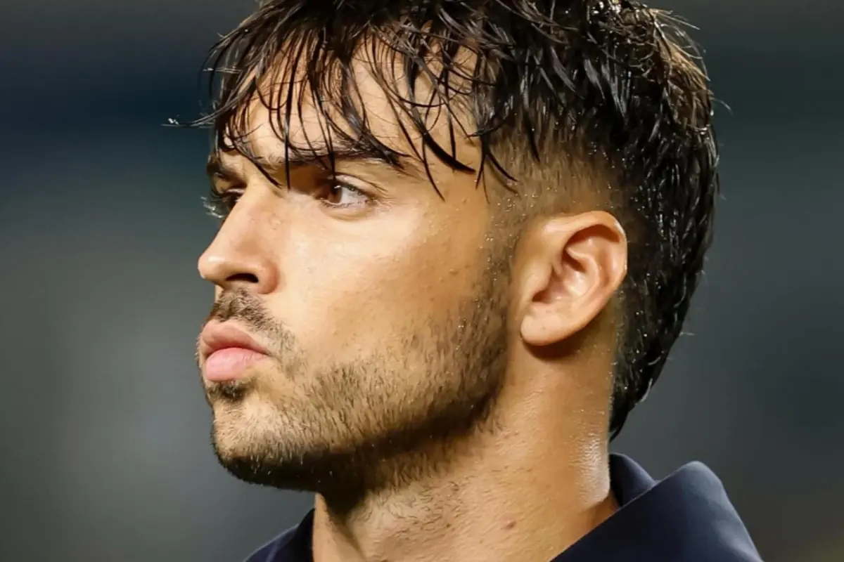 Home jove de perfil amb els cabells molls i barba curta mirant cap a l'esquerra