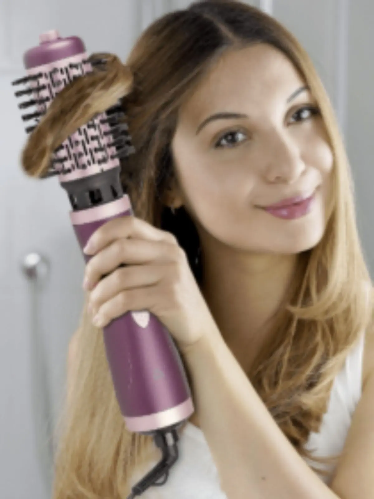 Mujer peinando su cabello largo con un cepillo secador eléctrico de color morado de Aldi.