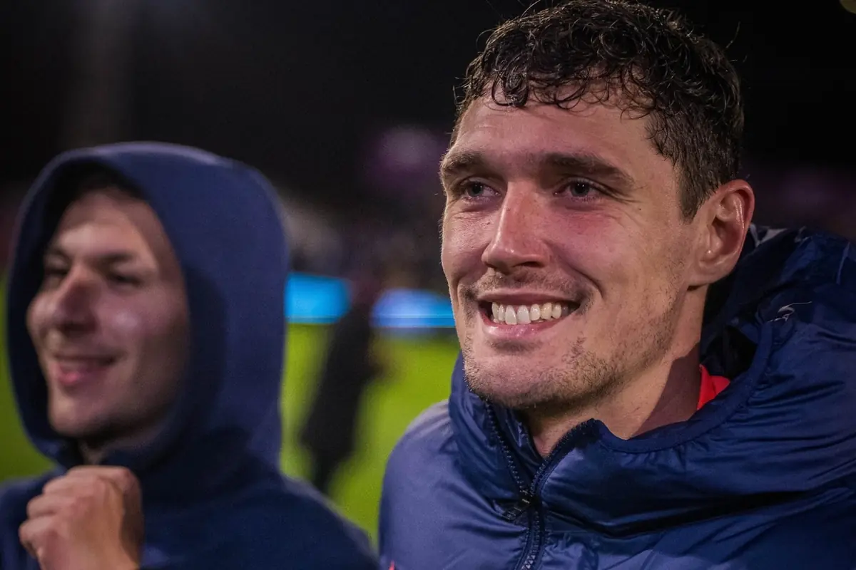 Dos homes somrients amb jaquetes esportives en un estadi il·luminat a la nit