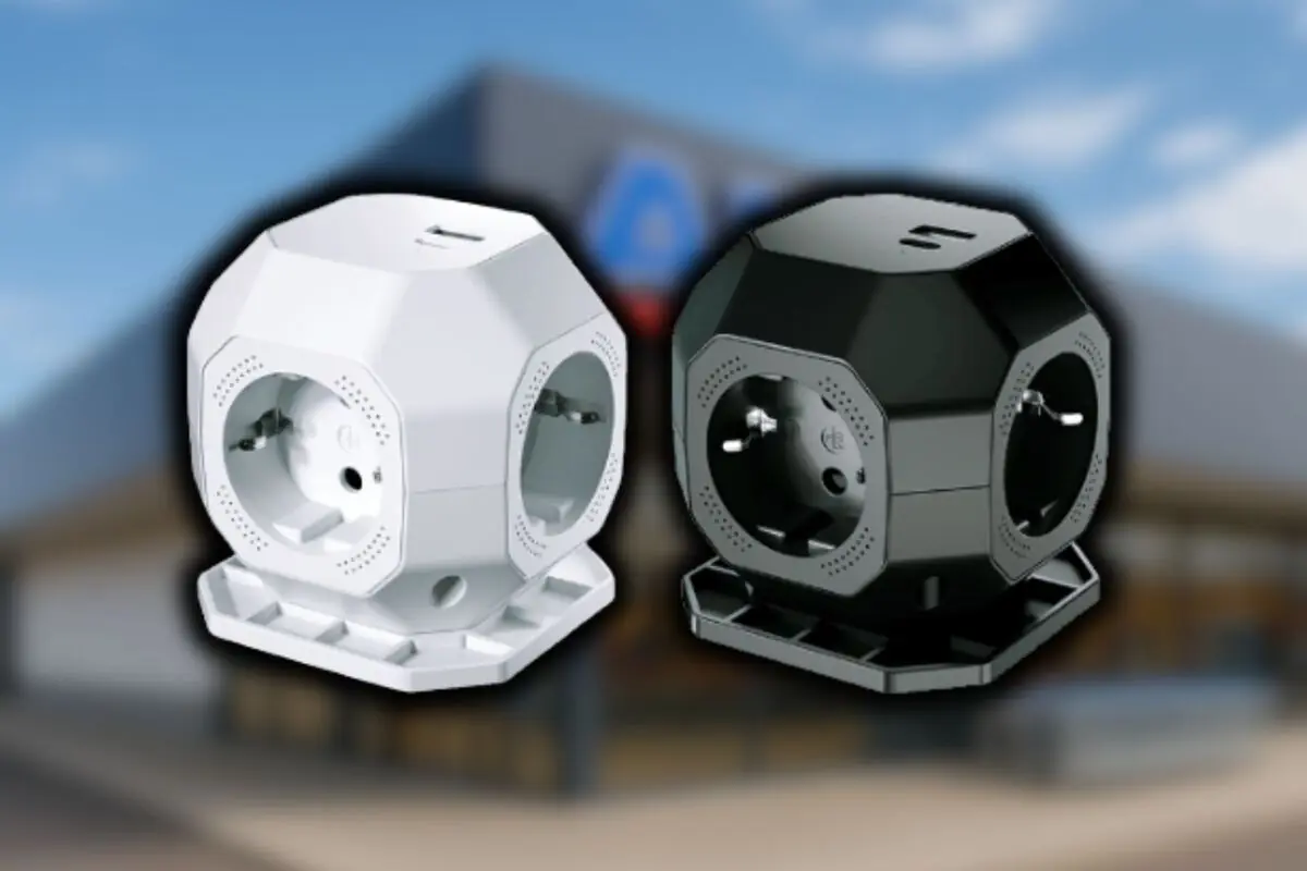 Dos regletas de enchufes en forma de cubo, una blanca y una negra, sobre un fondo desenfocado de una tienda Aldi.