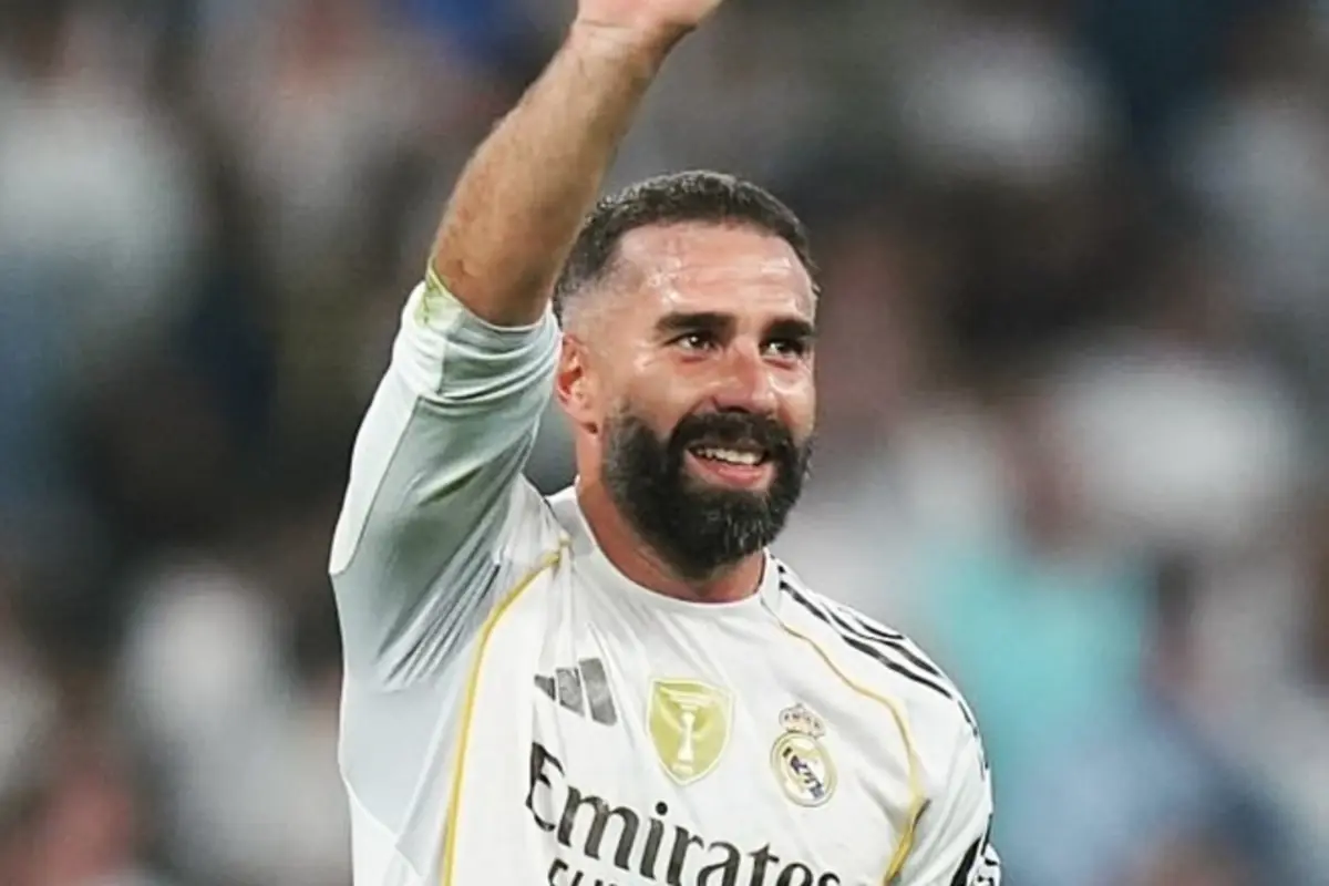 Futbolista del Reial Madrid amb barba i samarreta blanca aixecant el braç i somrient al camp