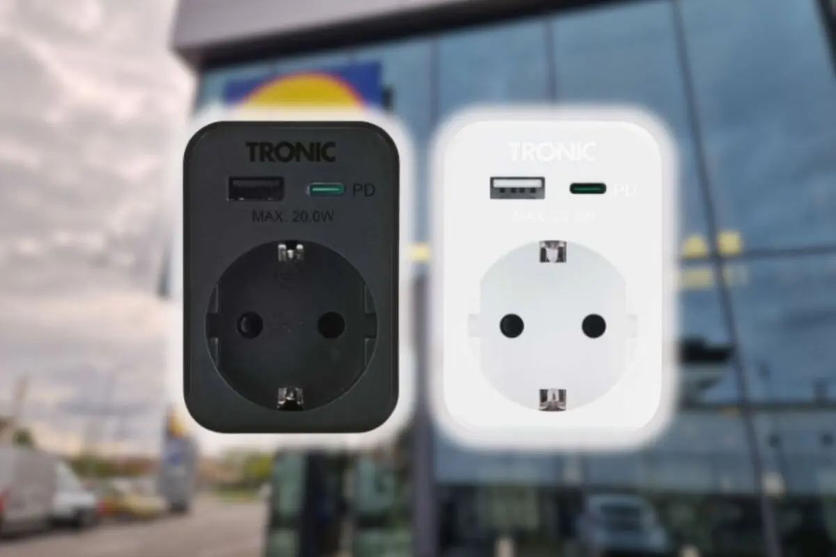 Two TRONIC smart plugs in black and white with USB and USB-C ports floating in front of the glass façade of a commercial building