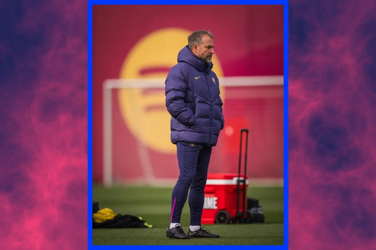 Entrenador de fútbol con chaqueta azul observando un entrenamiento en un campo con fondo rojo y amarillo