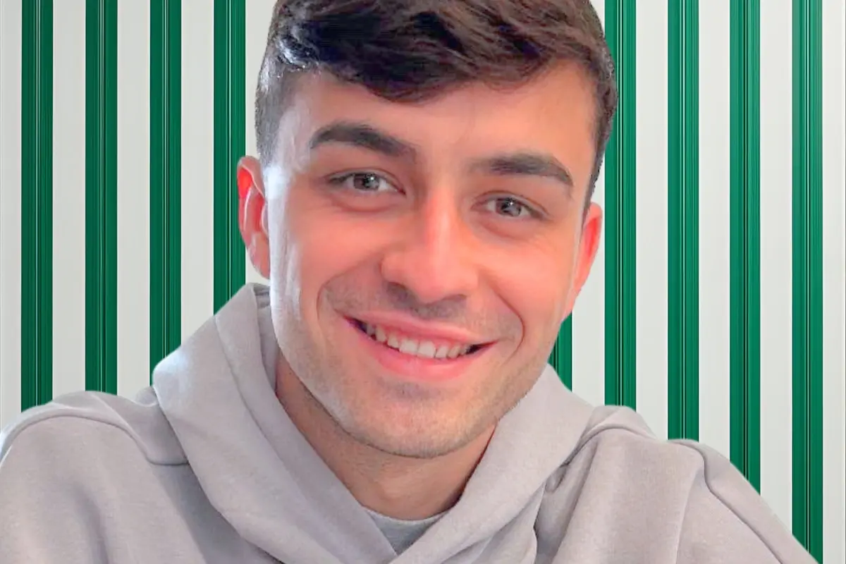 Smiling young man in a gray sweatjersey in front of a green and white striped background