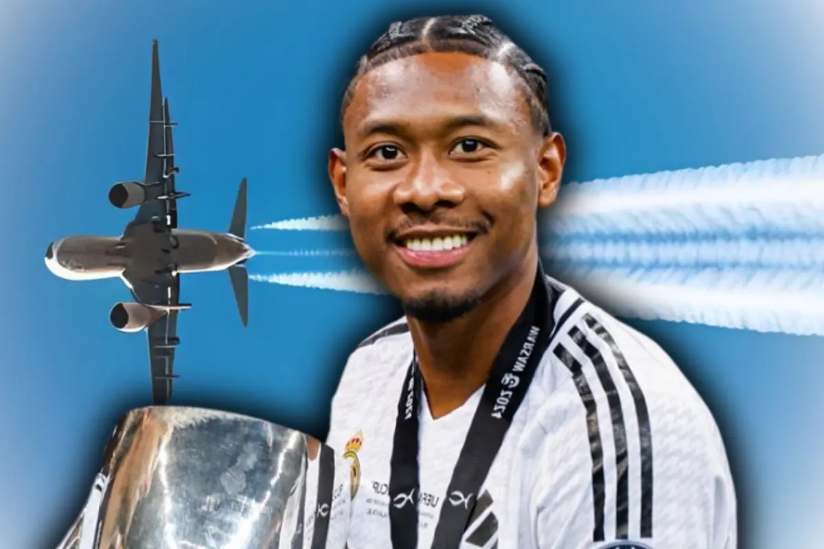 Muntatge d’un futbolista somrient amb uniforme blanc i medalla sostenint un trofeu platejat mentre un avió vola al darrere deixant esteles al cel blau