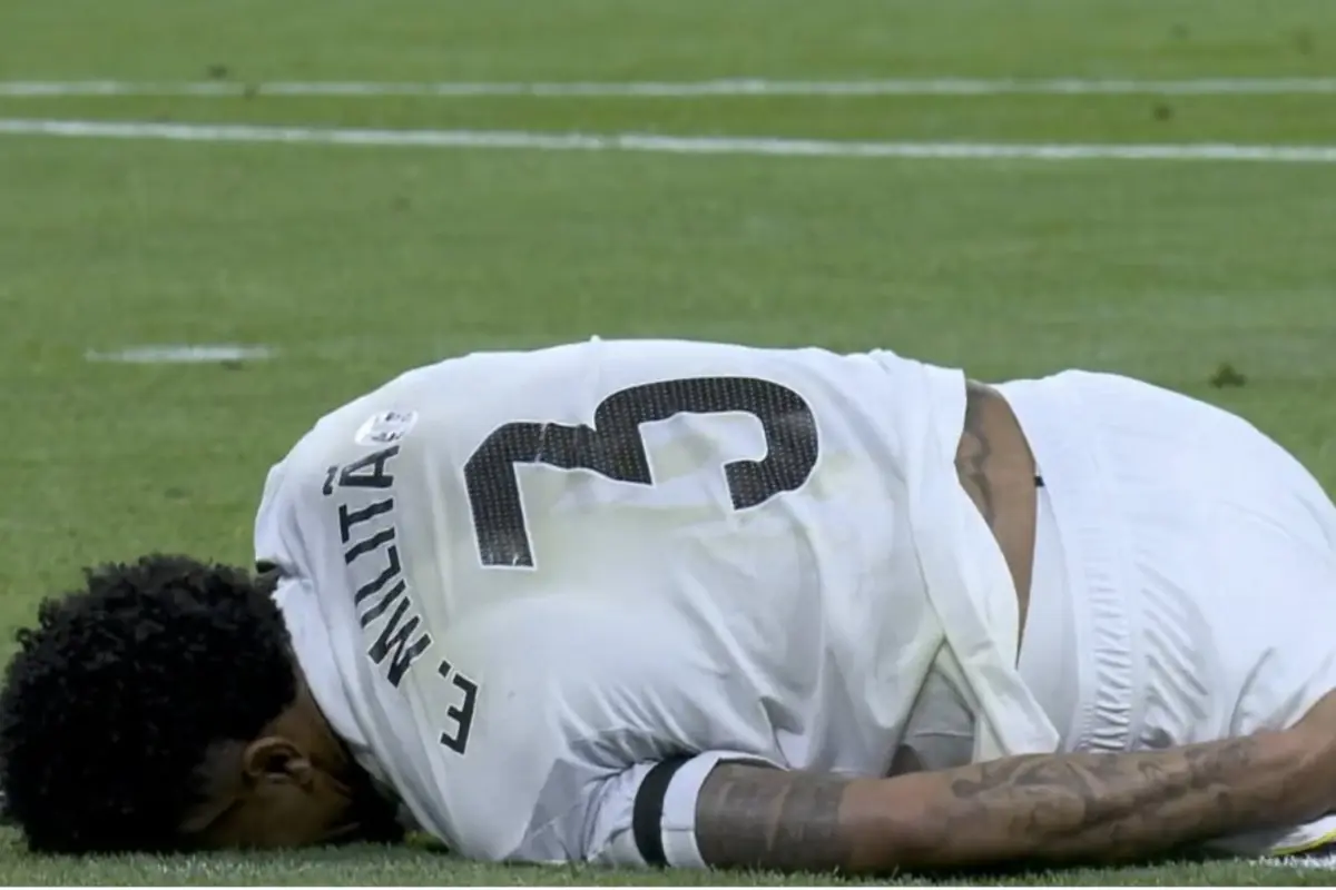 Futbolista del Real Madrid lesionado en el campo, mostrando dolor y siendo asistido por compañeros y personal del equipo