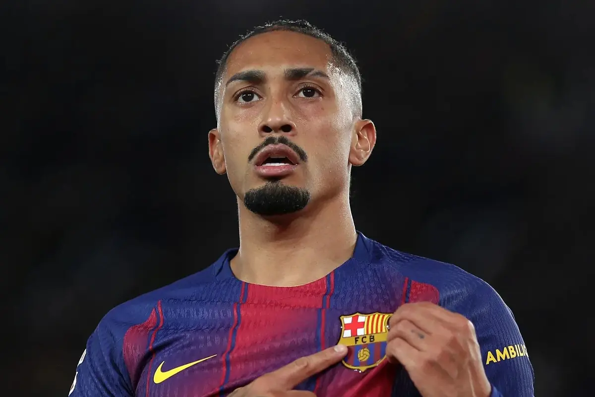 Futbolista amb l’uniforme del FC Barcelona assenyalant l’escut de l’equip a la seva samarreta