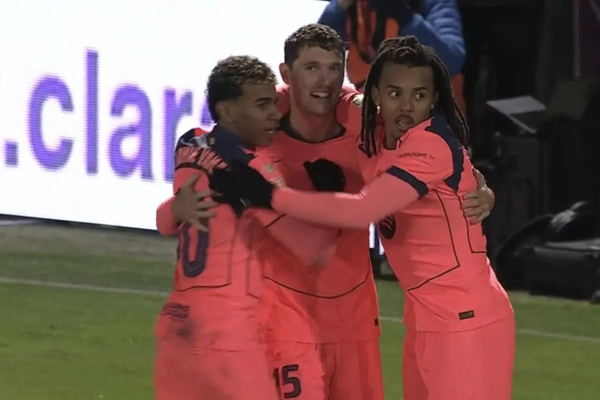 Tres futbolistes amb uniforme rosa s’abracen celebrant un gol al camp de joc