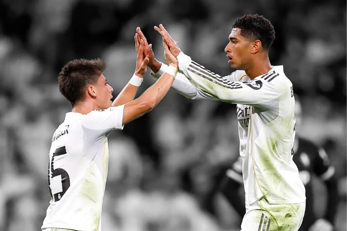Two Real Madrid players celebrate together on the field by high-fiving during a match.