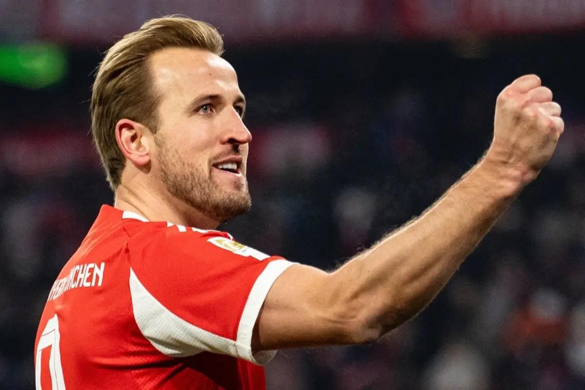 Soccer player in a red uniform celebrating with a raised fist in a stadium
