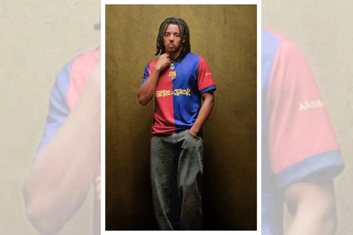Young man wearing a blue and red Barcelona jersey posing in front of a beige wall