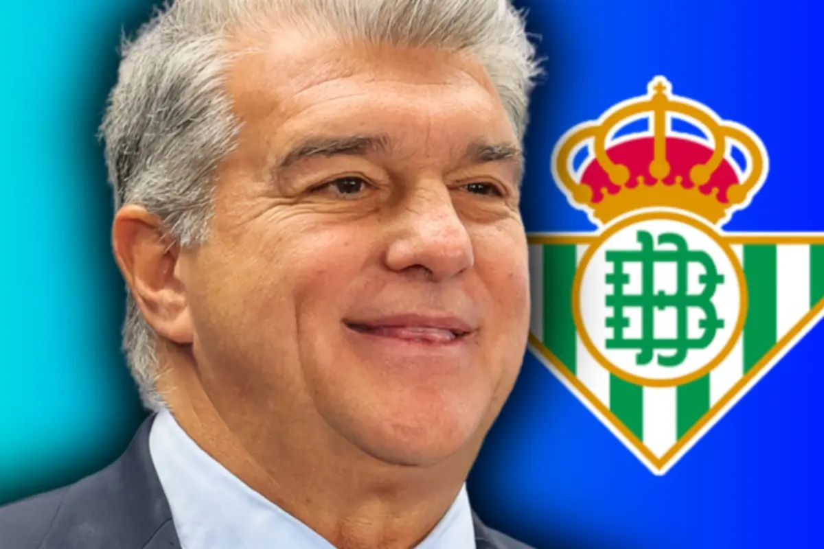 Smiling gray-haired man with a Real Betis crest in the background against a blue backdrop