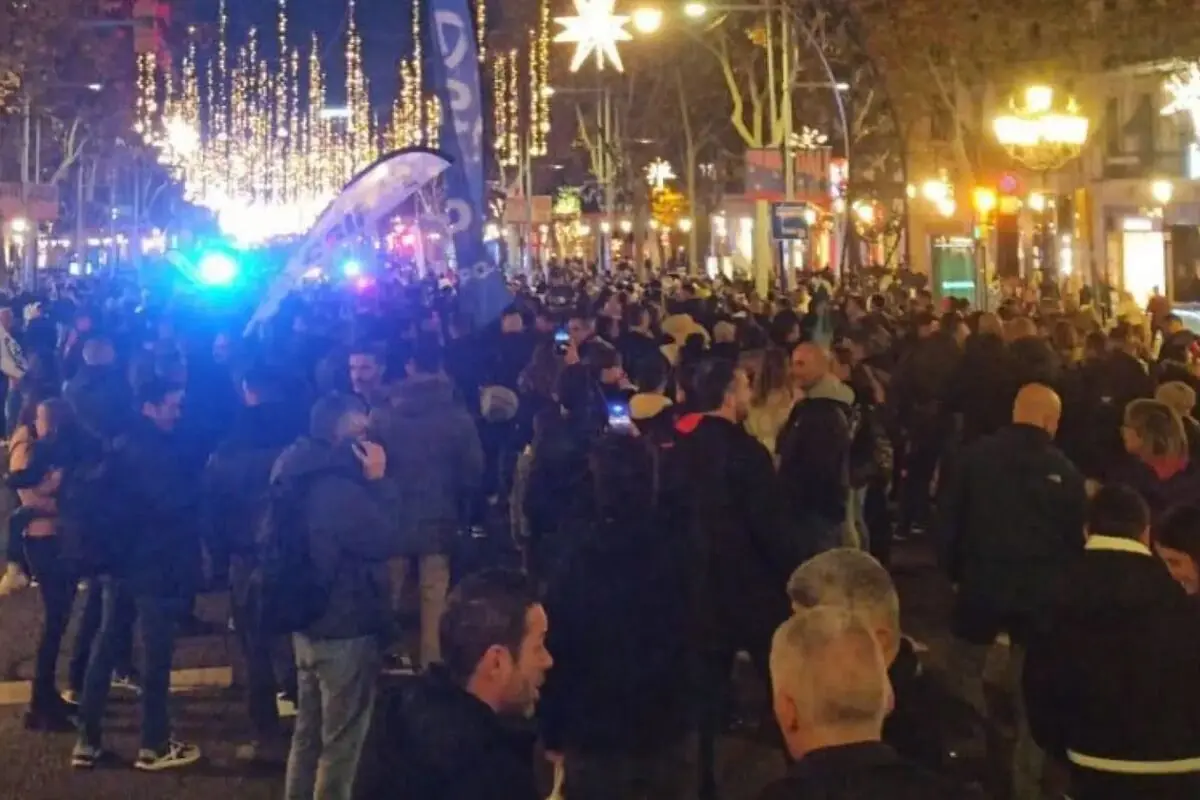 Multitud de persones reunides en un carrer il·luminat amb llums i decoracions de Nadal durant la nit. Multitud de persones reunides en un carrer il·luminat amb llums i decoracions de Nadal durant la nit.