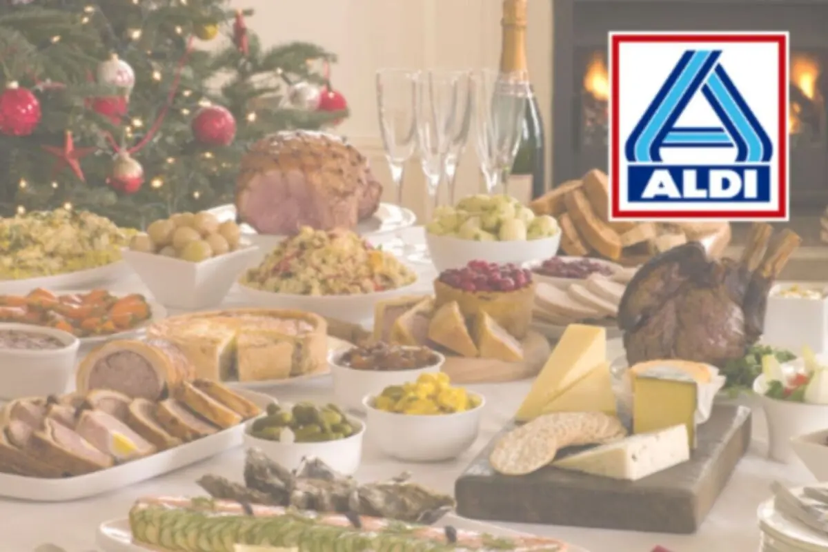Mesa festiva con variedad de alimentos y bebidas frente a un árbol de Navidad decorado y el logotipo de ALDI en la esquina superior derecha.