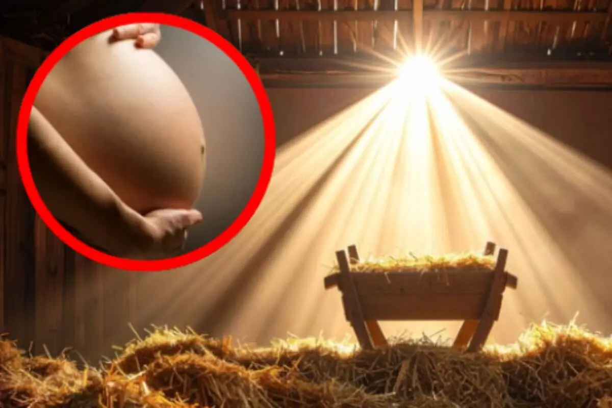 Ventre de dona embarassada en un cercle vermell al costat d’un pessebre il·luminat per raigs de llum en un estable.