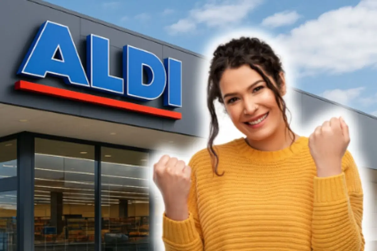 Mujer sonriente con suéter amarillo celebrando frente a la fachada de un supermercado ALDI.