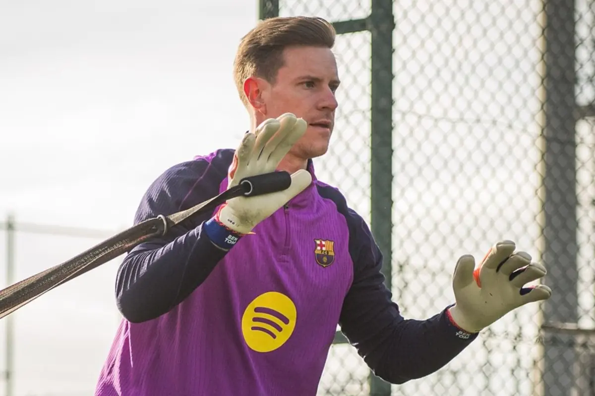 Porter entrenant amb guants i uniforme del FC Barcelona mentre sosté una corda elàstica en un camp de futbol a l’aire lliure