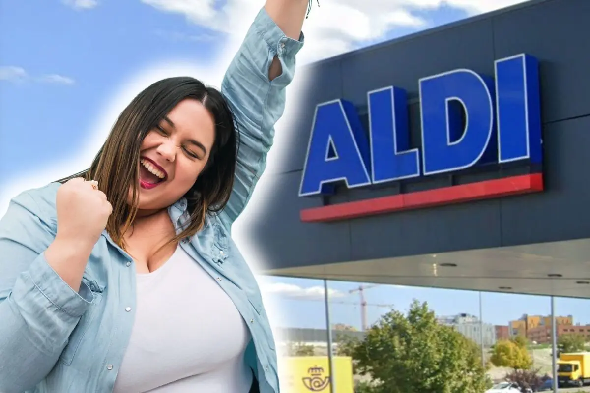 Dona somrient aixecant el braç en gest de celebració al costat de la façana d’un supermercat Aldi.