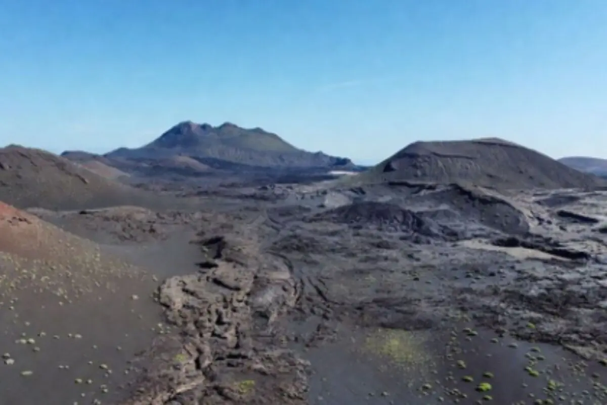 Paisatge volcànic àrid de Lanzarote amb colades de lava fosca i diversos cons sota un cel serè.