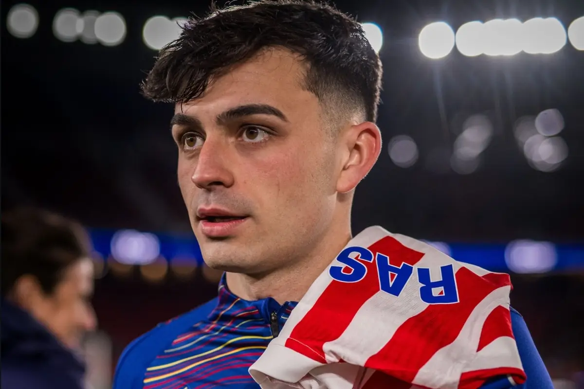 Jove futbolista amb samarreta blava i una bufanda vermella i blanca sobre l’espatlla en un estadi il·luminat