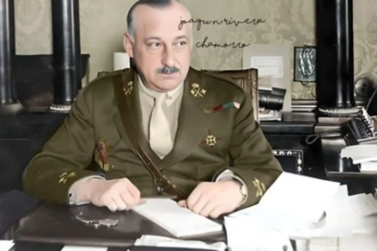 Hombre con bigote y uniforme militar, que es Primo de Rivera, sentado en un escritorio con papeles y objetos de oficina.