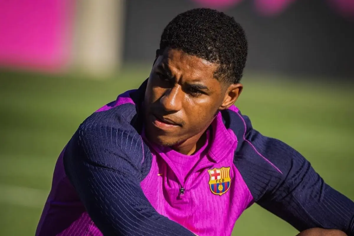 Futbolista amb uniforme d'entrenament del FC Barcelona assegut al camp mirant cap a un costat