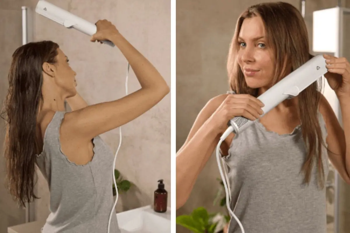 Mujer usando una herramienta eléctrica de Aldi para alisar su cabello en el baño mientras viste una camiseta gris sin mangas.