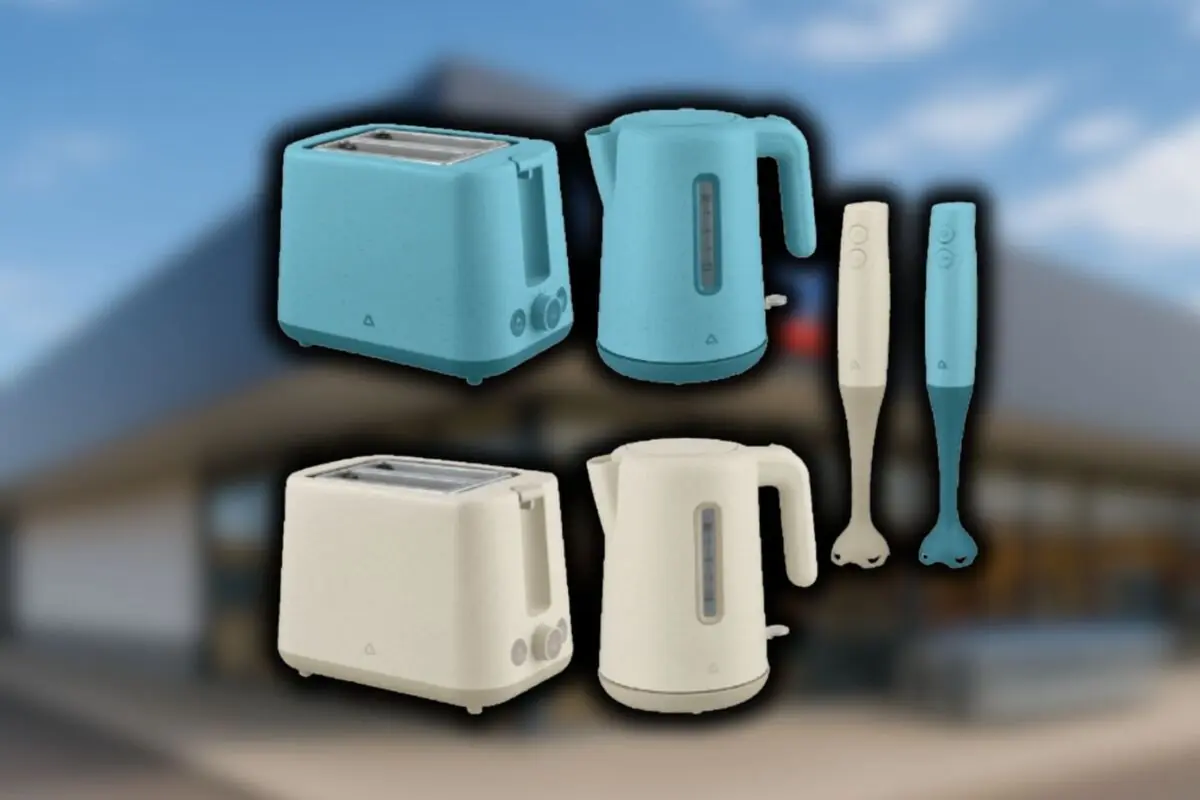 Electrodomésticos de cocina en color azul y beige incluyendo tostadoras, hervidores y batidoras de mano sobre un fondo desenfocado de una tienda Aldi.