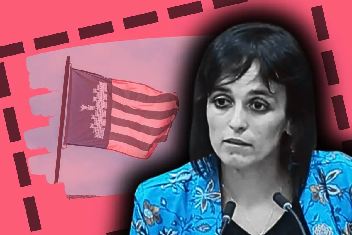 Primer plano de Sílvia Orriols con expresión seria frente a micrófonos y bandera de Mallorca ondeando al fondo sobre un diseño gráfico en tonos rosas.
