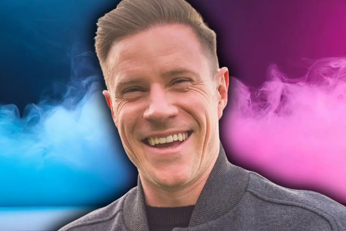 Hombre sonriente con fondo de humo azul y rosa